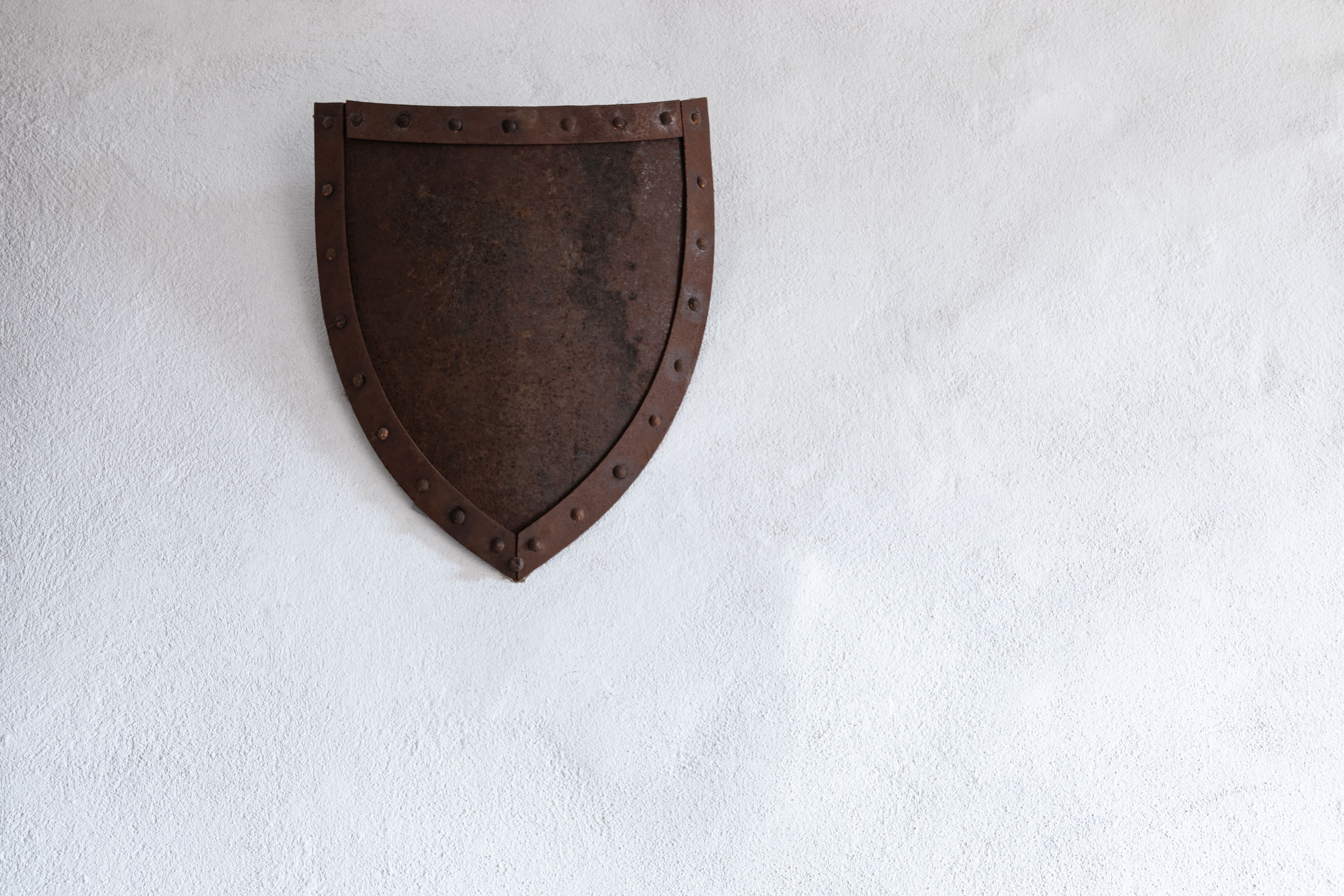 Old rusted shield hung on a light colored wall