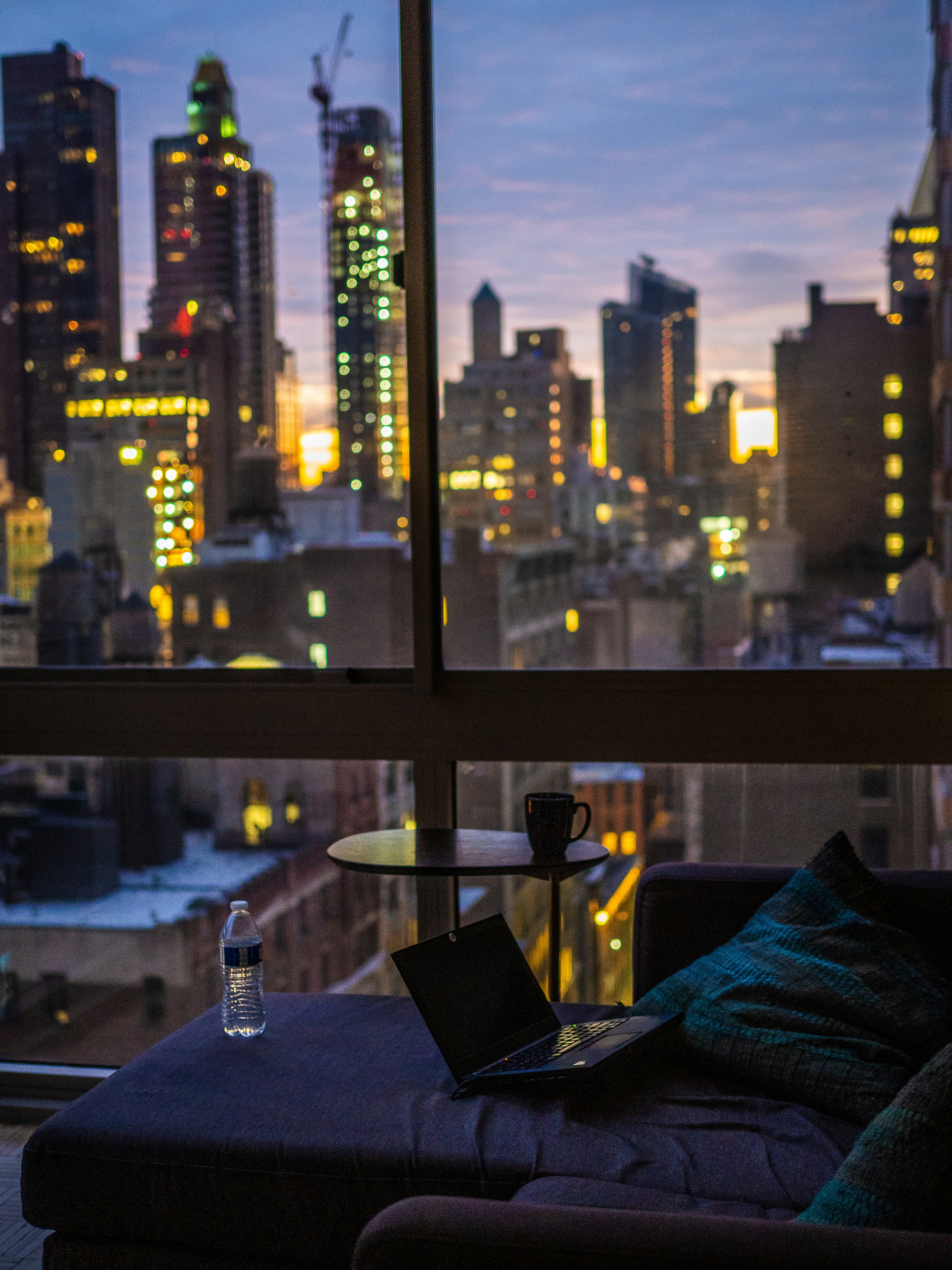 Photo of a laptop by a coffee table witha view of new york city